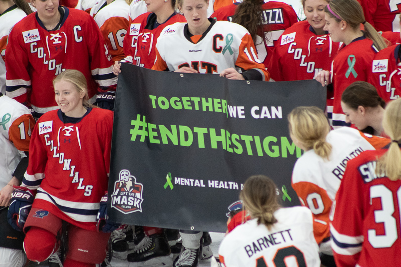 Both teams gather around the #EndtheStigma banner before the start of the Mental Health Awareness game. Neville Island, PA Friday Jan. 25, 2019. (RMU Sentry Media/Samuel Anthony)